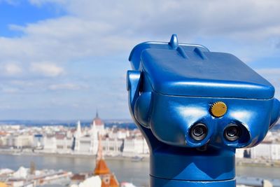 Close-up of coin-operated binoculars against cityscape