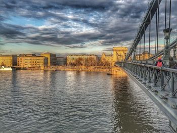 Bridge over river against cloudy sky