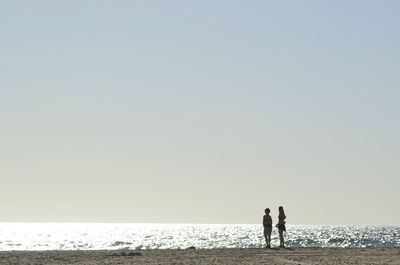 People on beach against clear sky