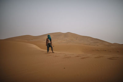 Full length of woman on sand dune in desert against clear sky