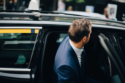 Side view of businessman entering taxi in city