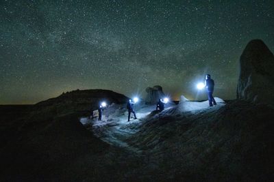 People on rock against sky at night