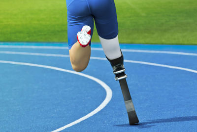 Low section of athlete running with prosthetic leg on track