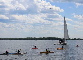 People on sailboat in river against sky