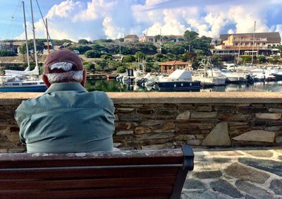 Rear view of man relaxing on old town against cloudy sky