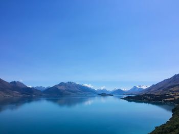 Scenic view of lake amidst mountains against clear blue sky
