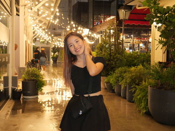 Portrait of young woman standing against trees