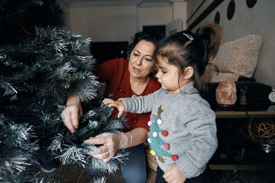 Grandparents decorate the christmas tree with their little granddaughter