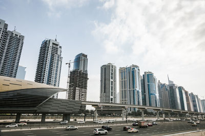 Cars on street amidst buildings in city against sky