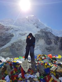 Full length of man standing on snowcapped mountain against sky