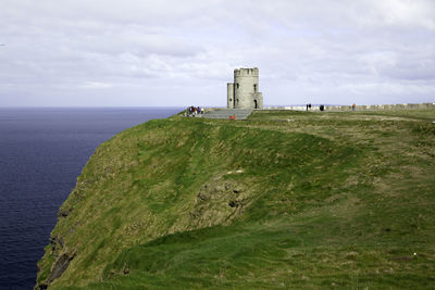 Scenic view of cliff at coastline against clouds