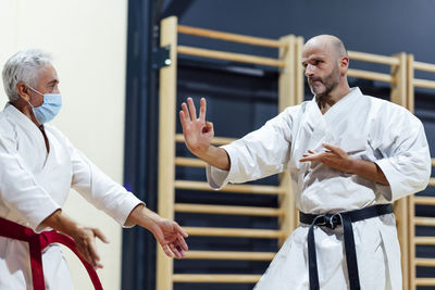 Male student practicing karate by instructor in class