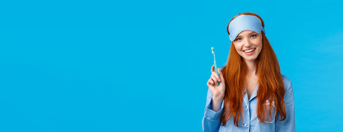 Low angle view of woman standing against blue background