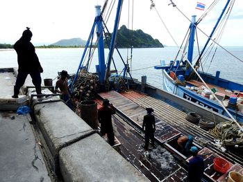 People working in boat moored on sea against sky