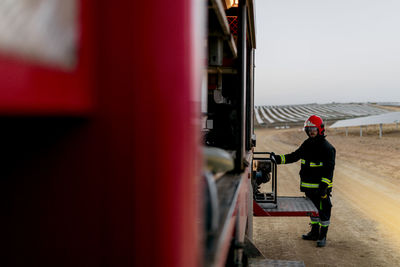 Side view of a firefighter removing a portable light generator from the side of the fire truck