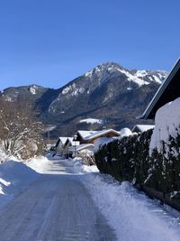 Snow covered road by mountain against sky