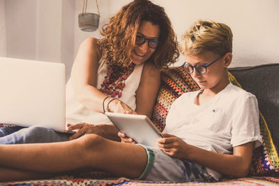 Young woman using mobile phone while sitting on laptop