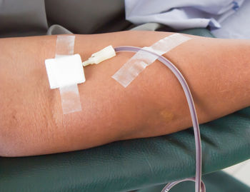 Close-up of syringe inserted on human hand at hospital