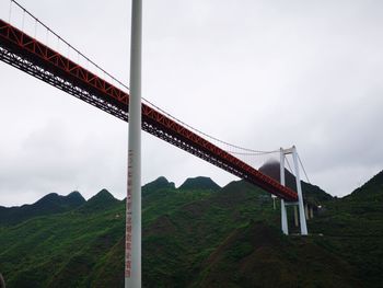 Low angle view of suspension bridge against sky