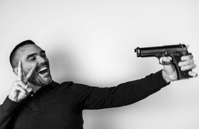 Portrait of man holding camera against white background