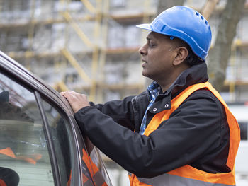 Side view of man standing in car