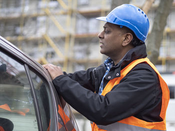 Side view of man standing in car