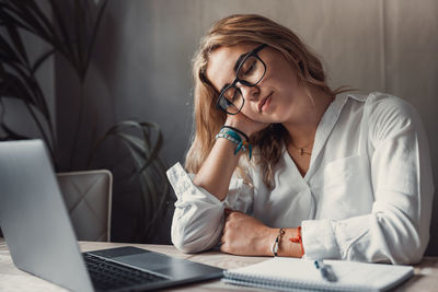 Young woman talking on phone while sitting at desk in office