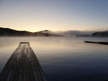 Pier over lake against sky during sunset