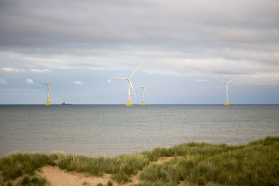 Wind turbines on land against sky