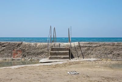 Deck chairs on beach against clear sky