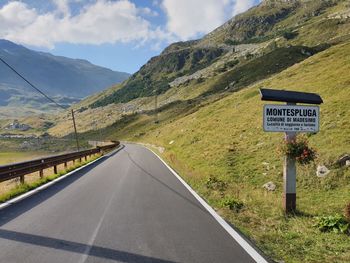 Information sign by road against sky