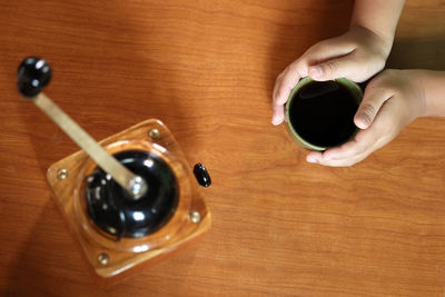 High angle view of hand holding coffee cup on table