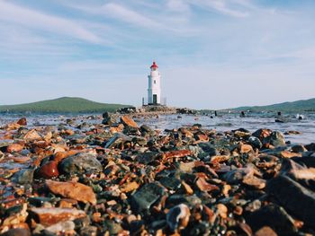 Lighthouse by sea against sky