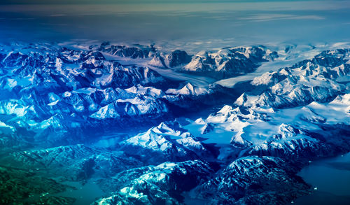 Aerial view of snowcapped mountains against blue sky