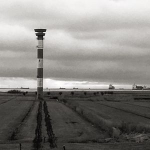 Lighthouse on field against sky