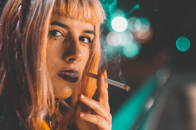 Close-up portrait of young woman smoking cigarette