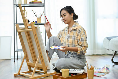 Side view of young woman sitting on chair at home