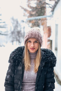 Portrait of smiling young woman standing in snow