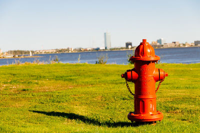 Orange fire hydrant on grass against clear sky