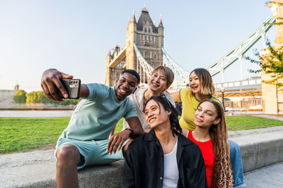 Portrait of smiling friends standing against sky