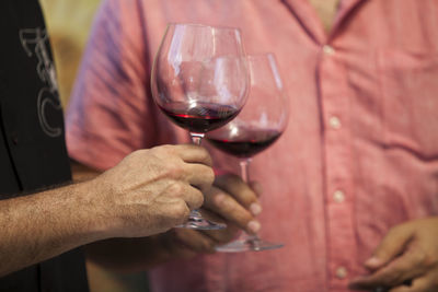 Midsection of man holding wineglass