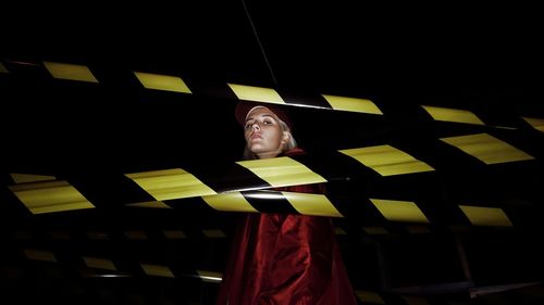 Portrait of woman standing by cordon tapes at night