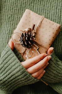 Female hands holding nice gift box. woman giving wrapped in craft paper present. cozy gift wrapping