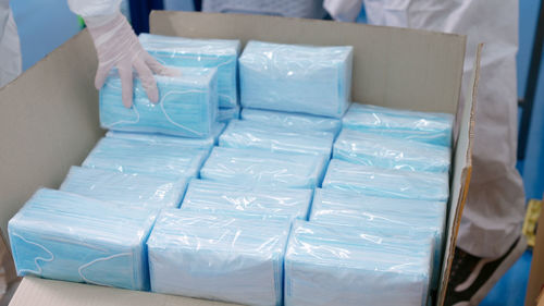 Cropped hand packing masks at factory