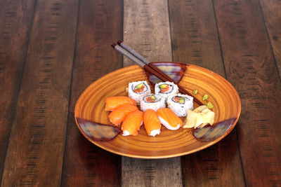 Salmon sushi rolls and sake with wasabi, ginger and chopsticks