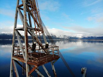 High angle view of bald eagles perching on metallic tower against lake and sky