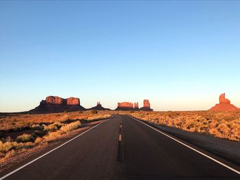 Road amidst desert against clear sky