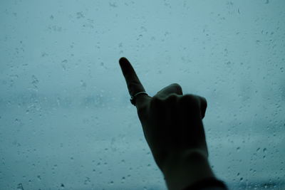 Close-up of human hand against sky