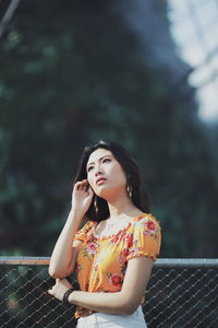 Beautiful young woman standing against railing