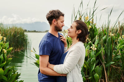 Side view of couple embracing by lake